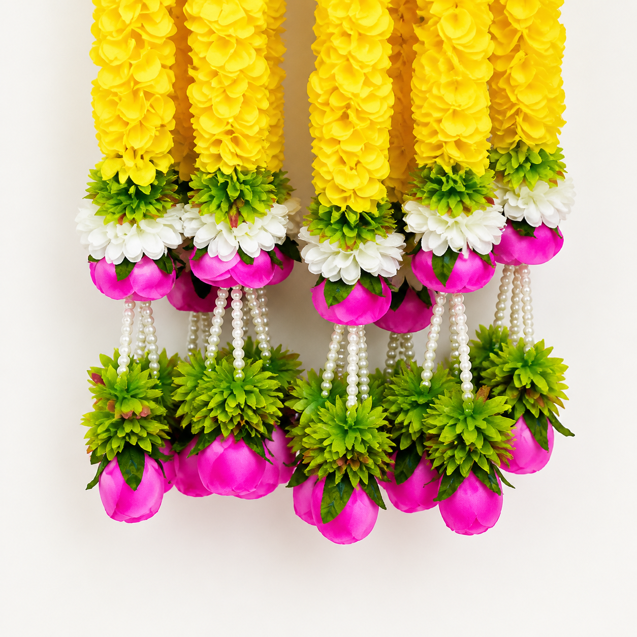 Close-up of yellow, white and pink artificial flowers with green foliage and pearl tassels
