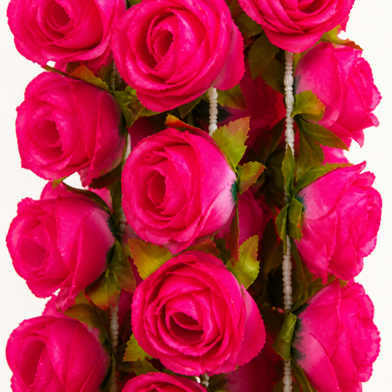 Close-up detail of rose red artificial flowers and green leaves on garland